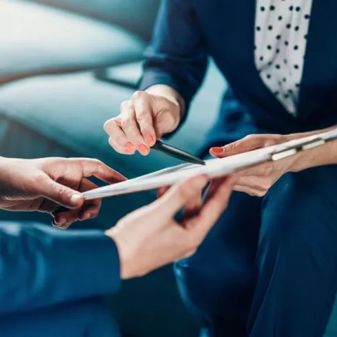 close up image of employment lawyer pointing at legal documents on a clipboard with a pen