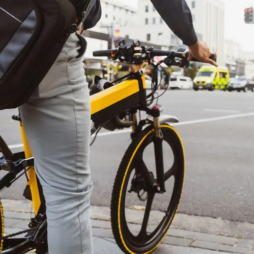 Male riding on a stationery yellow e-bike in San Francisco